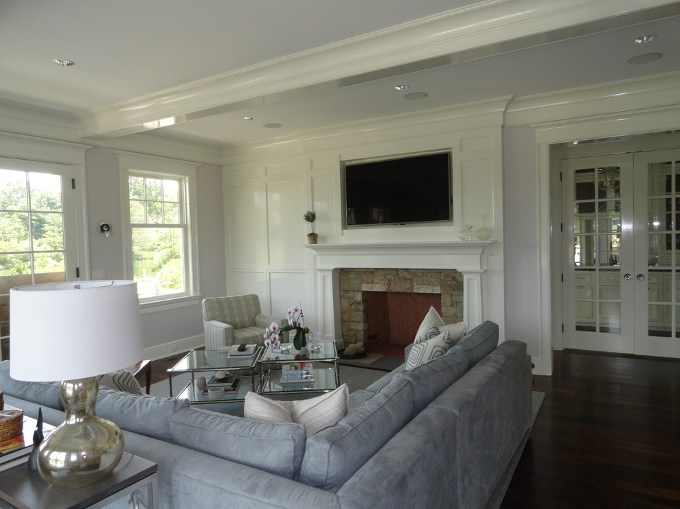 Large beach style open concept brown floor family room photo in New York with gray walls, a standard fireplace, a stone fireplace and a wall-mounted tv