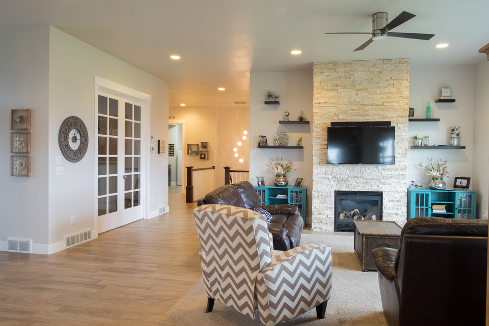 Стильный дизайн: открытая гостиная комната среднего размера в стиле кантри с серыми стенами, ковровым покрытием, двусторонним камином, фасадом камина из камня и телевизором на стене - последний тренд