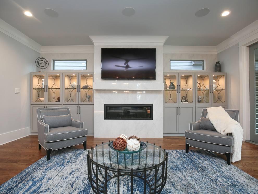 Источник вдохновения для домашнего уюта: большая изолированная гостиная комната в стиле неоклассика (современная классика) с серыми стенами, темным паркетным полом, стандартным камином, фасадом камина из плитки и телевизором на стене