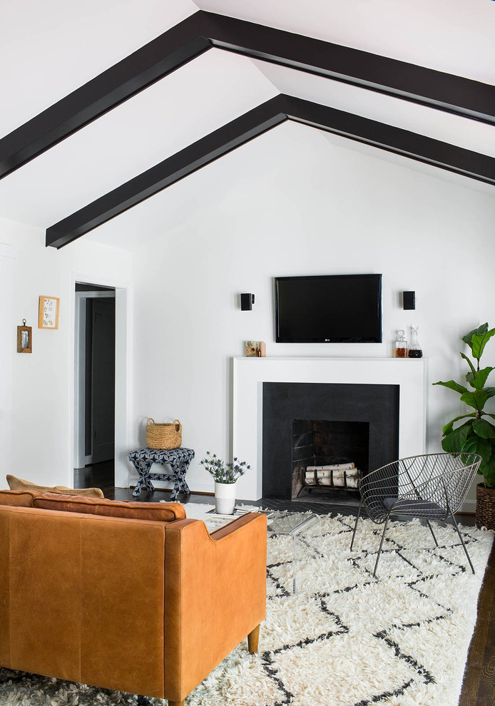 Immagine di un soggiorno chic aperto con pareti grigie, parquet scuro, camino classico, cornice del camino in pietra e TV a parete