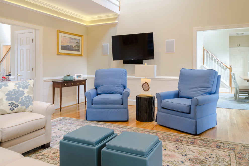Modelo de sala de estar abierta clásica renovada de tamaño medio con paredes beige, suelo de madera en tonos medios y televisor colgado en la pared