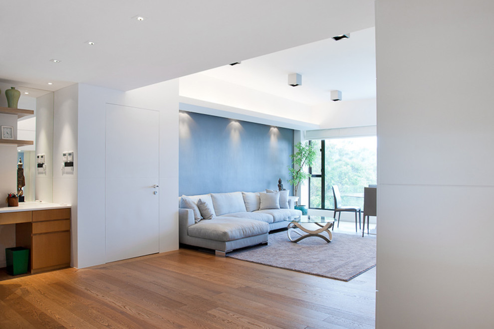 Cette photo montre une grande salle de séjour tendance ouverte avec un mur blanc, un sol en bois brun et un téléviseur encastré.