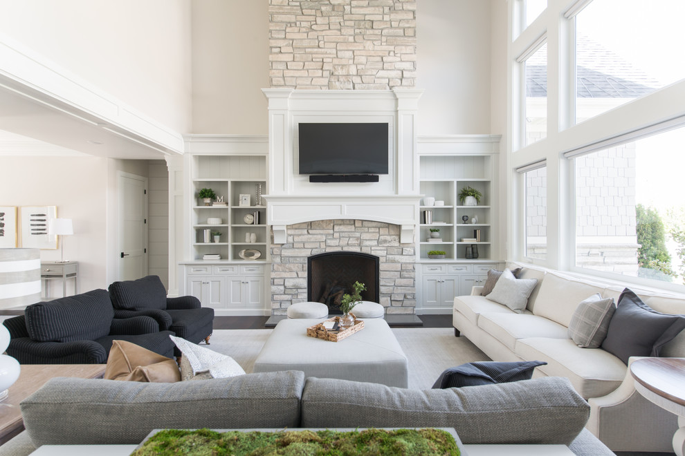 Стильный дизайн: гостиная комната в стиле неоклассика (современная классика) с бежевыми стенами, стандартным камином, фасадом камина из камня, телевизором на стене и черным полом - последний тренд