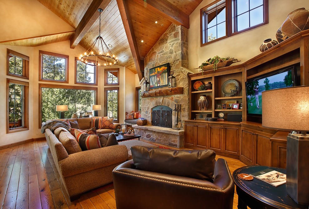 Inspiration for a huge southwestern open concept medium tone wood floor family room remodel in Salt Lake City with a standard fireplace, a stone fireplace, a media wall and yellow walls