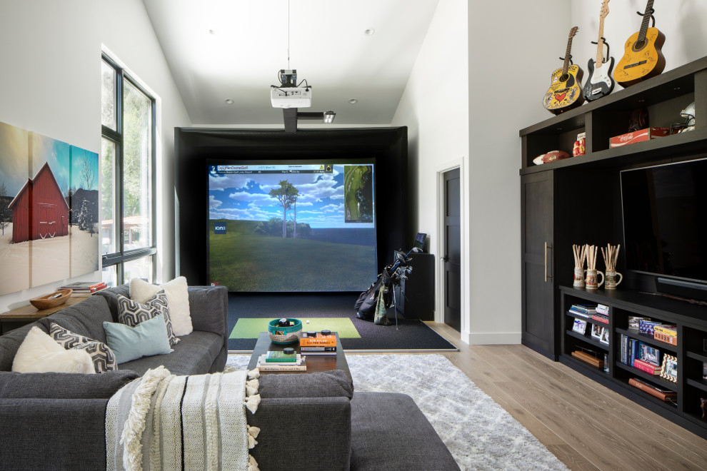 Example of a transitional medium tone wood floor, brown floor and vaulted ceiling game room design in Denver with white walls and a media wall