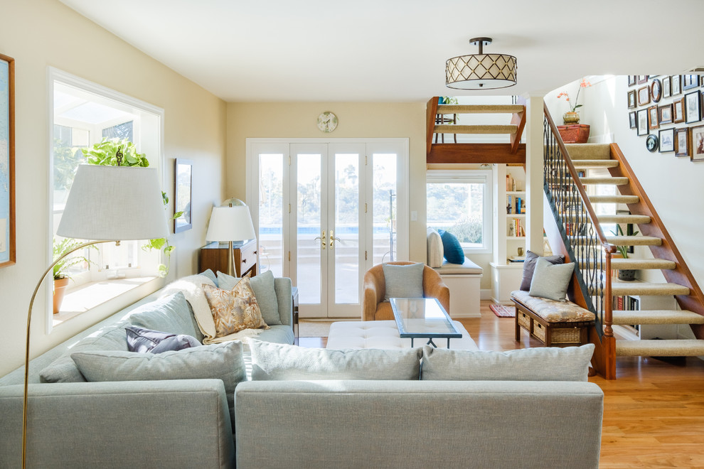 Imagen de sala de estar cerrada costera de tamaño medio sin chimenea con paredes beige, suelo de madera clara y suelo marrón