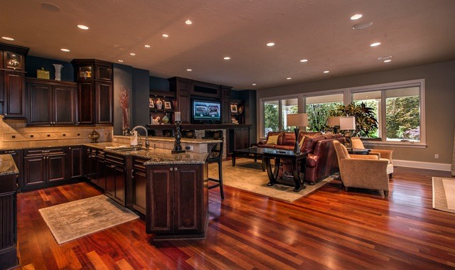 Game room - large mediterranean open concept dark wood floor and brown floor game room idea in Seattle with beige walls, a standard fireplace, a wood fireplace surround and a media wall