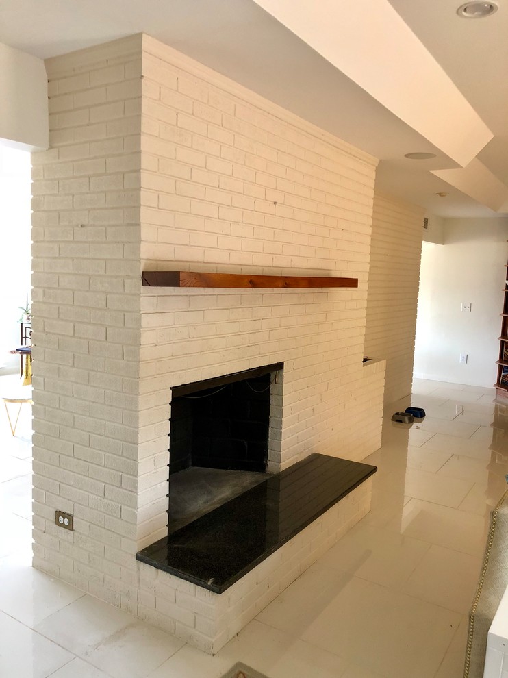 Ejemplo de sala de estar clásica renovada de tamaño medio con paredes blancas, suelo de baldosas de cerámica, chimenea de doble cara, marco de chimenea de ladrillo y suelo blanco