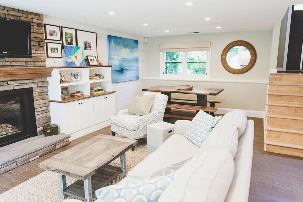Inspiration for a medium sized coastal open plan games room in Providence with a home bar, white walls, porcelain flooring, a standard fireplace, a stone fireplace surround, a wall mounted tv and brown floors.