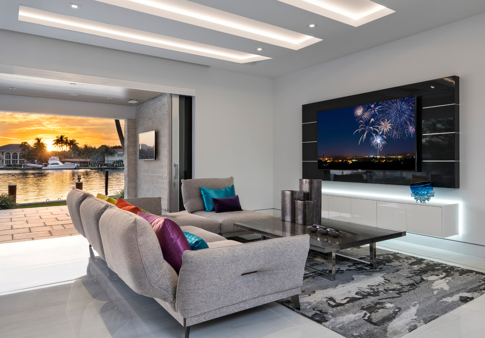 Diseño de sala de estar abierta contemporánea de tamaño medio sin chimenea con paredes blancas, televisor colgado en la pared, suelo gris y alfombra