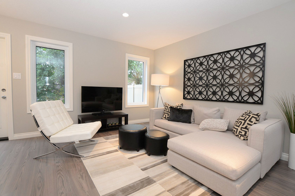 Imagen de sala de estar abierta contemporánea pequeña con paredes grises y suelo de madera clara
