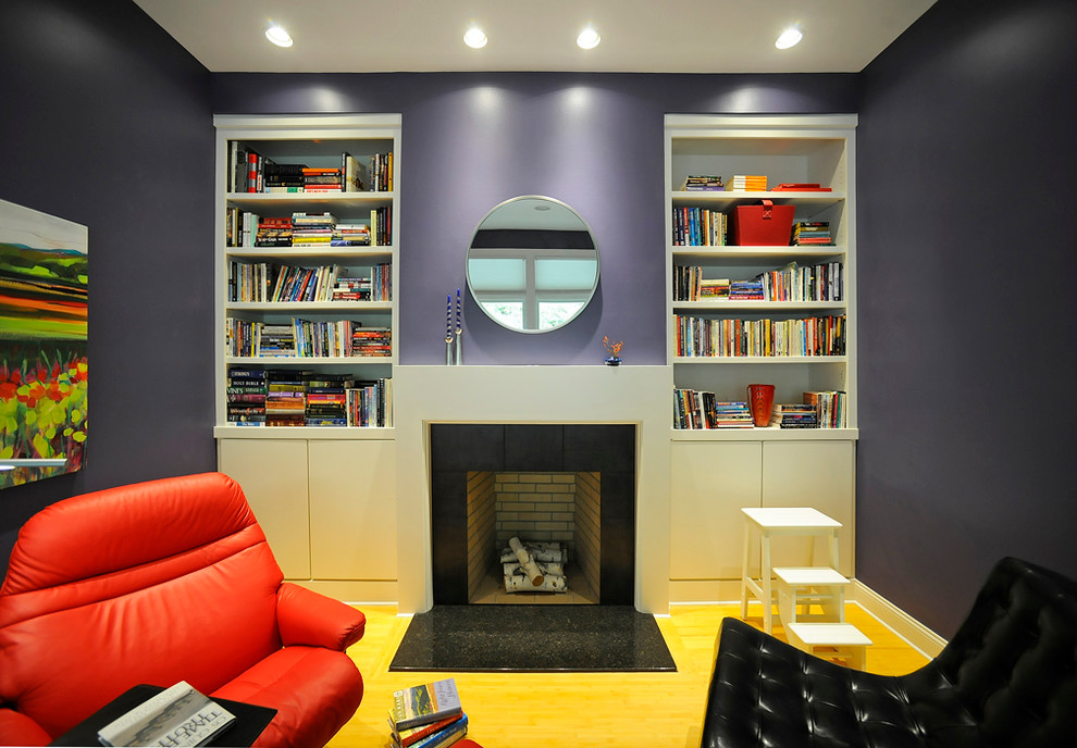 Diseño de sala de estar con biblioteca minimalista con paredes púrpuras, suelo de madera clara, todas las chimeneas, marco de chimenea de piedra y suelo amarillo