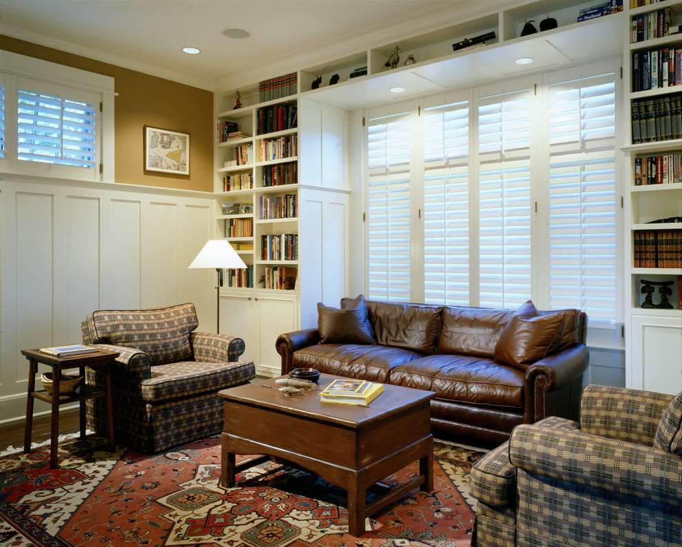 Imagen de sala de estar con biblioteca cerrada clásica sin chimenea con suelo de madera oscura y paredes beige