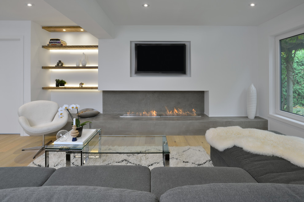 Mittelgroßes, Offenes Modernes Wohnzimmer mit weißer Wandfarbe, Sperrholzboden, Gaskamin, Kaminumrandung aus Beton, Multimediawand und braunem Boden in Toronto