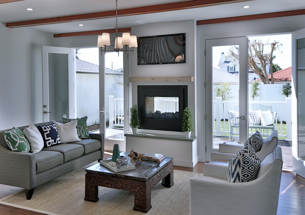 Foto de sala de estar tradicional renovada de tamaño medio con paredes blancas, suelo de madera en tonos medios, chimenea de doble cara y televisor colgado en la pared