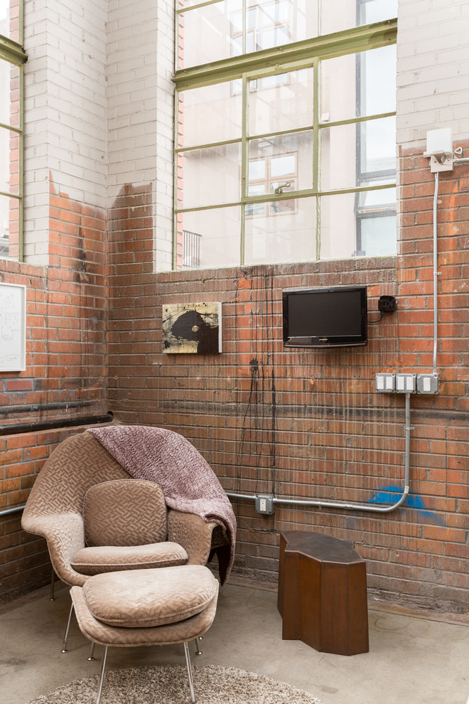 Diseño de sala de estar urbana con paredes multicolor, suelo de cemento y televisor colgado en la pared