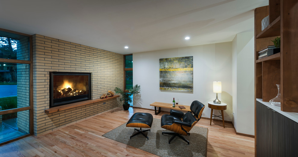 Cette image montre une salle de séjour vintage ouverte avec un mur blanc, parquet clair, une cheminée standard, un manteau de cheminée en brique et aucun téléviseur.