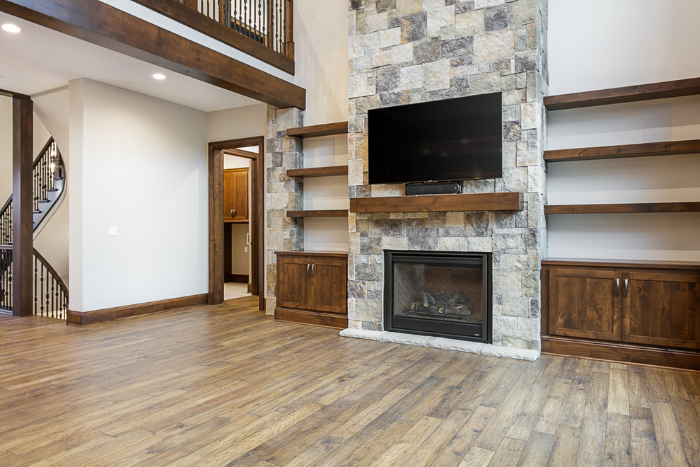 オマハにある広いトラディショナルスタイルのおしゃれなオープンリビング (白い壁、無垢フローリング、標準型暖炉、石材の暖炉まわり、壁掛け型テレビ、茶色い床) の写真