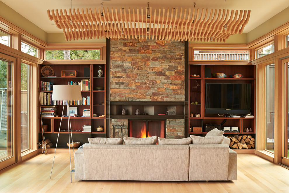 This is an example of a medium sized contemporary open plan games room in Other with light hardwood flooring, a standard fireplace, a built-in media unit, a reading nook and beige walls.
