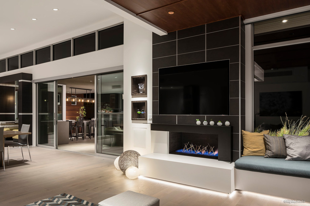 Example of a mid-sized trendy open concept light wood floor and beige floor family room design in Phoenix with a tile fireplace, a media wall, white walls and a ribbon fireplace