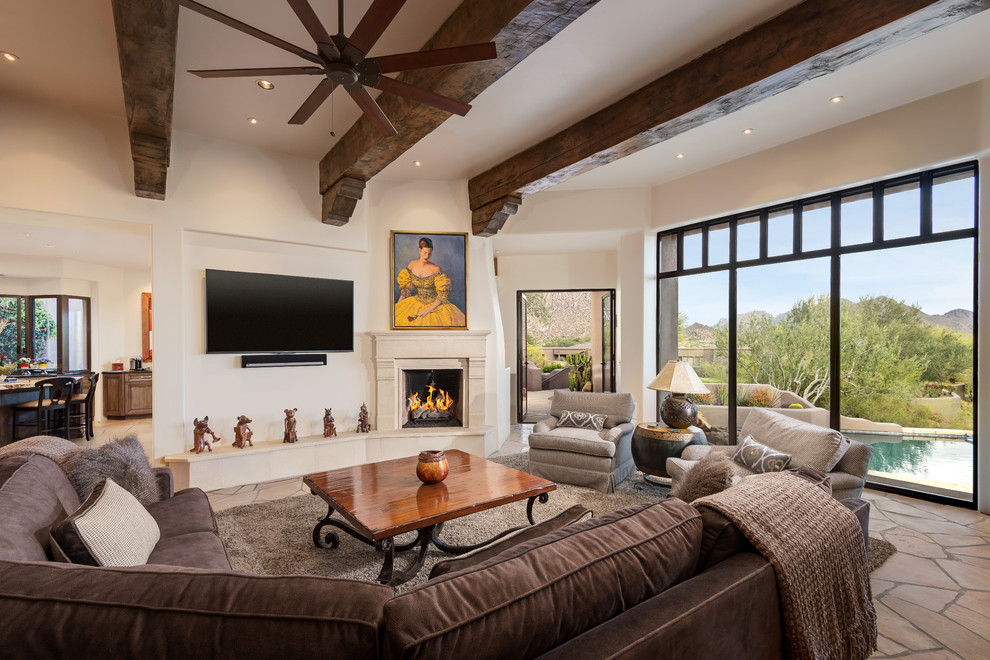 Ejemplo de sala de estar abierta de estilo americano grande con todas las chimeneas, televisor colgado en la pared, paredes beige, marco de chimenea de yeso y alfombra