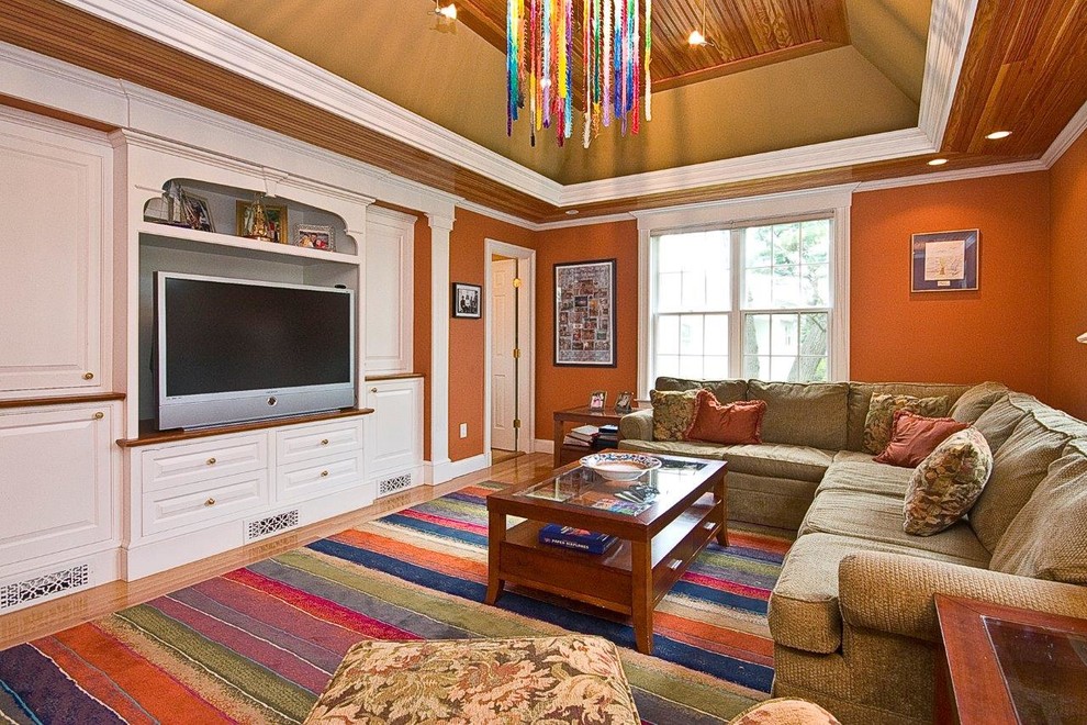 Ejemplo de sala de estar clásica con parades naranjas, suelo de madera clara y pared multimedia