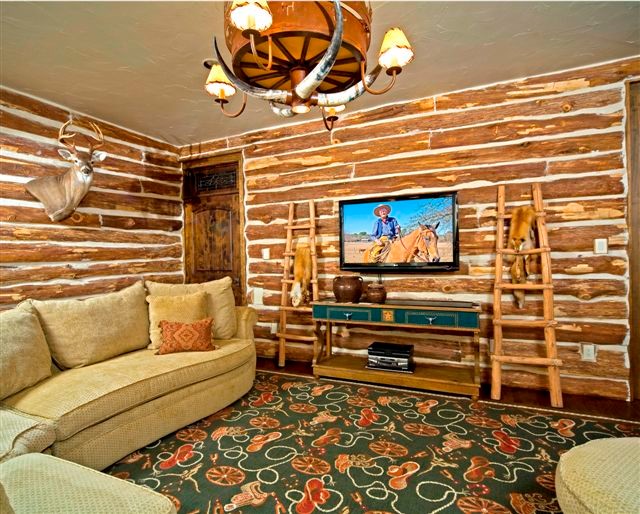 Foto de sala de estar abierta rural extra grande con paredes marrones y televisor colgado en la pared