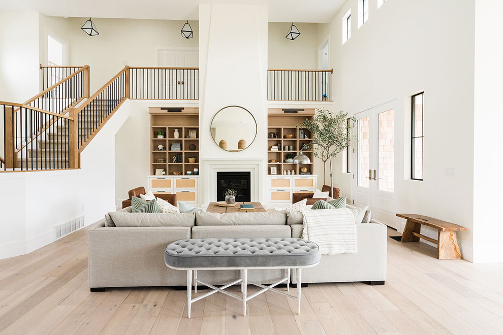 Ejemplo de sala de estar abierta clásica renovada con paredes blancas, suelo de madera clara, todas las chimeneas y suelo beige