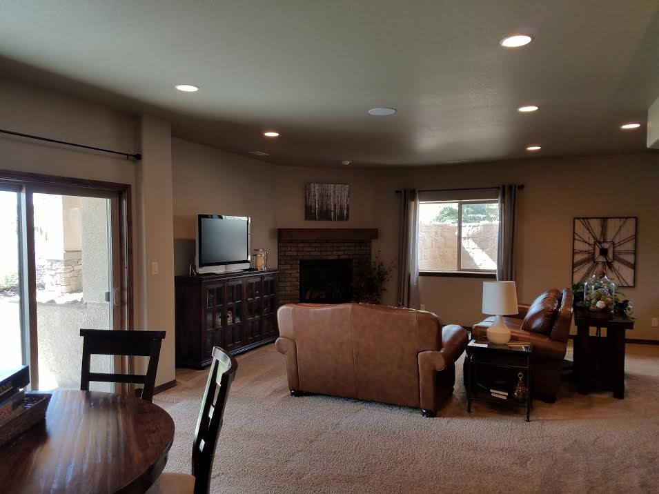 Inspiration for a medium sized traditional open plan games room in Denver with beige walls, carpet, a corner fireplace, a brick fireplace surround, a freestanding tv, beige floors and a game room.