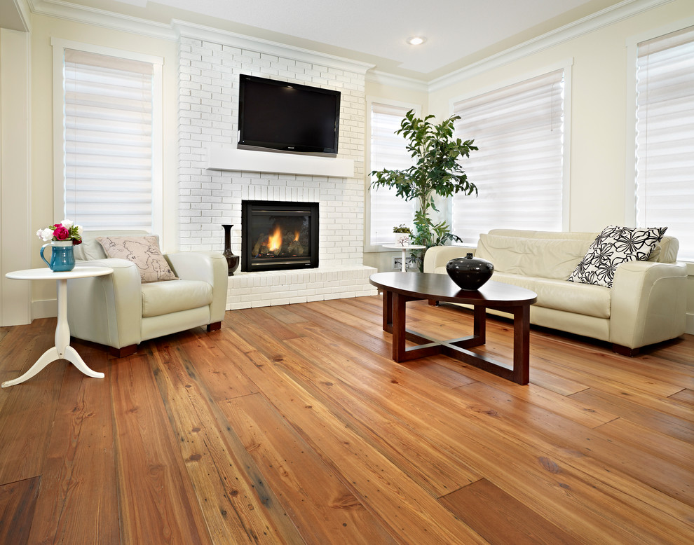 Modernes Wohnzimmer mit beiger Wandfarbe, braunem Holzboden, Kamin, Kaminumrandung aus Backstein, TV-Wand und braunem Boden in Edmonton