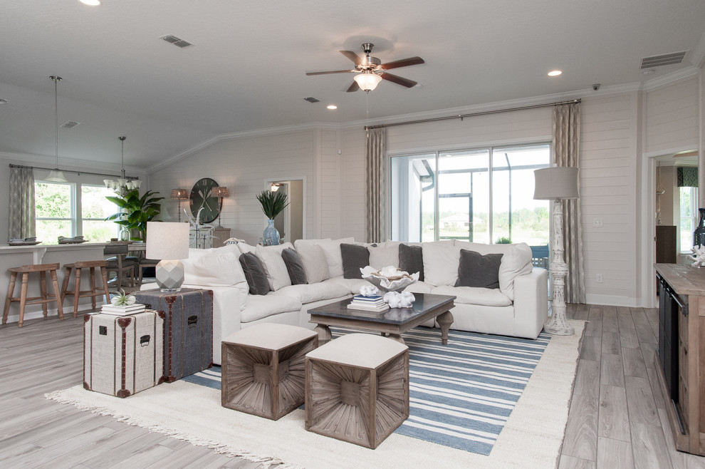 Immagine di un grande soggiorno costiero aperto con pareti bianche, pavimento con piastrelle in ceramica, TV a parete e pavimento beige