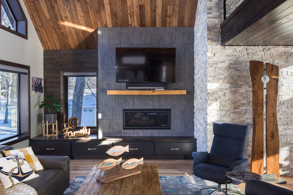 Ejemplo de sala de estar abierta rústica con paredes multicolor, suelo de madera clara, chimenea lineal, televisor colgado en la pared y alfombra