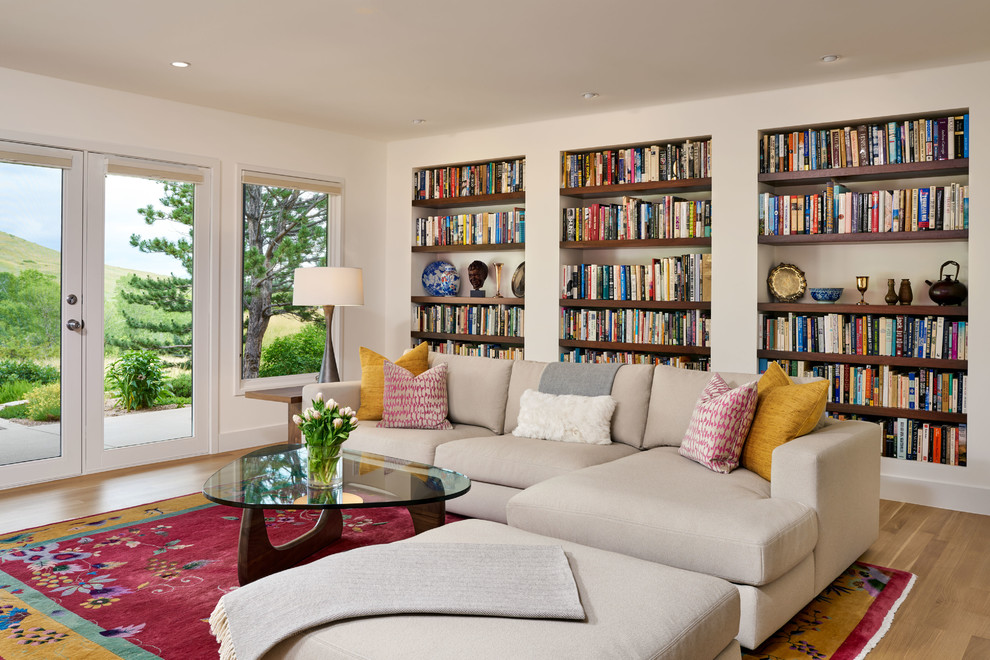 Aménagement d'une salle de séjour classique avec une bibliothèque ou un coin lecture, un mur beige, un sol en bois brun et un sol marron.