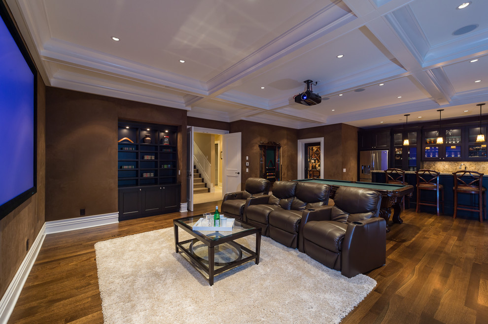 Modelo de sala de estar con barra de bar abierta tradicional grande sin chimenea con paredes marrones, suelo de madera en tonos medios y televisor colgado en la pared