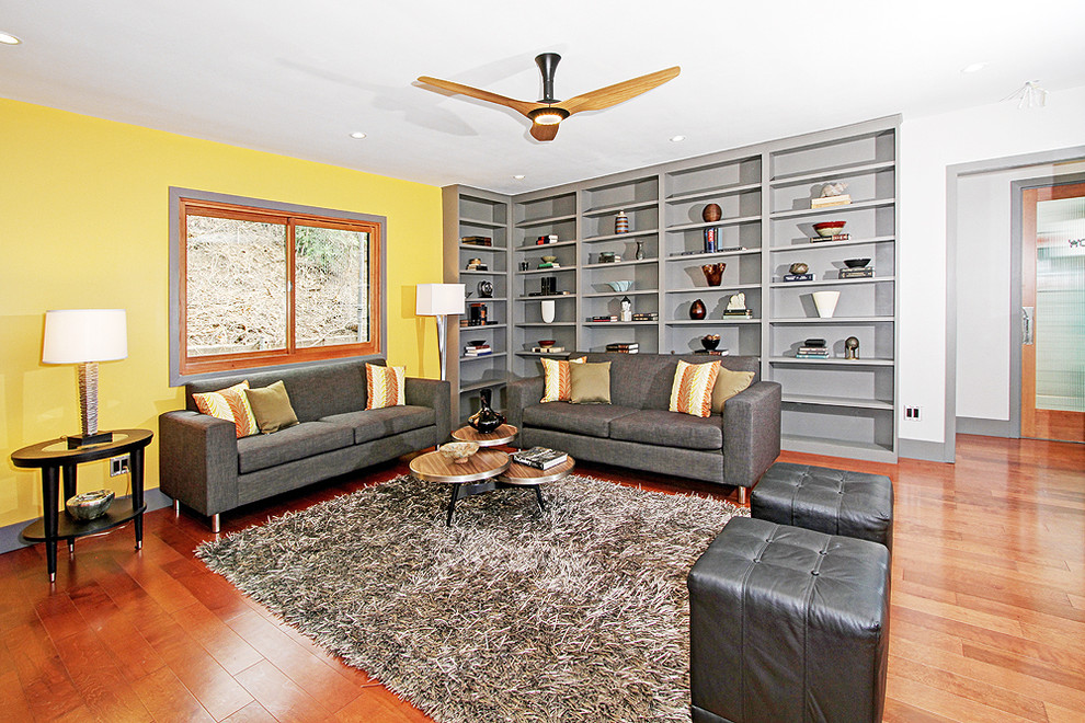 Immagine di un soggiorno minimalista chiuso con pareti gialle, pavimento in legno massello medio e nessun camino