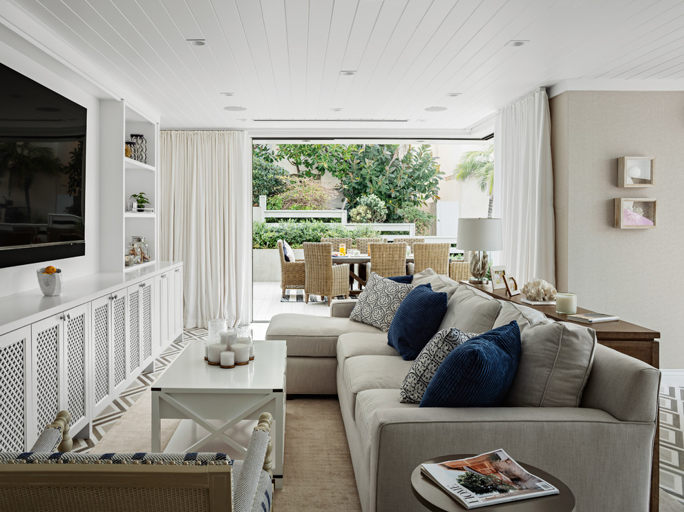 Foto de sala de estar abierta costera con paredes beige y pared multimedia