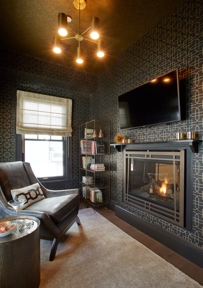 На фото: маленькая гостиная комната в стиле неоклассика (современная классика) с черными стенами, темным паркетным полом, двусторонним камином, фасадом камина из камня, телевизором на стене и коричневым полом для на участке и в саду с