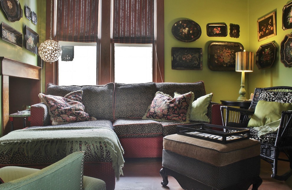 Modelo de sala de estar cerrada ecléctica pequeña sin chimenea con paredes verdes, suelo de madera en tonos medios y televisor retractable