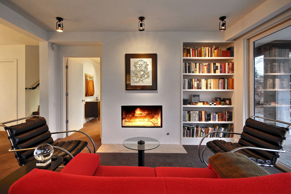 Immagine di un piccolo soggiorno moderno aperto con libreria, pareti bianche, camino classico, nessuna TV, cornice del camino in metallo e pavimento marrone