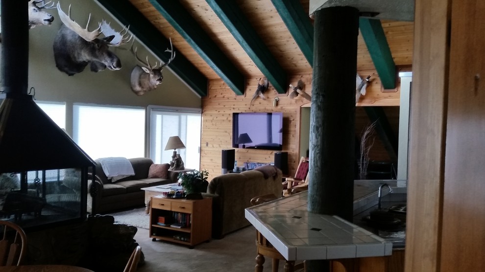 Foto di un grande soggiorno rustico aperto con sala giochi, pareti beige, moquette, stufa a legna, cornice del camino in pietra e TV a parete