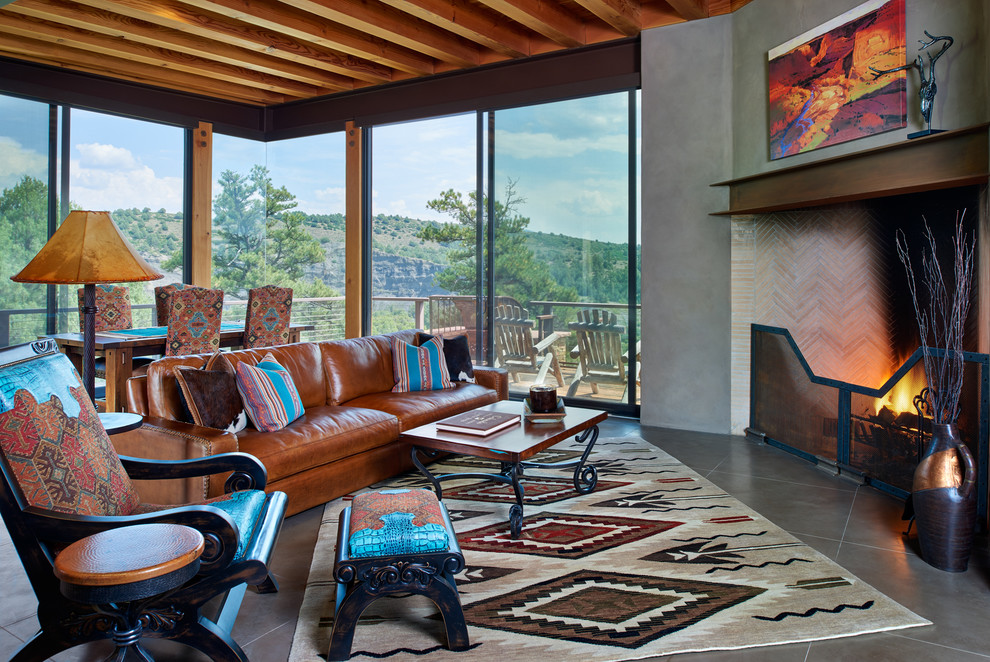 Cette image montre une salle de séjour sud-ouest américain ouverte avec un mur gris, une cheminée standard, un manteau de cheminée en carrelage et un sol gris.