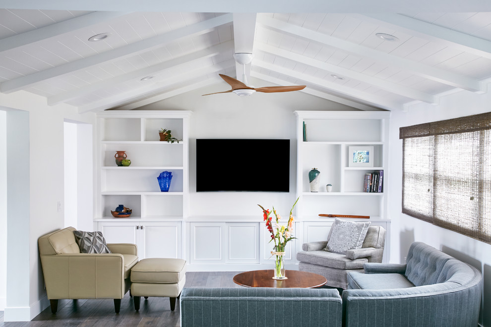 На фото: изолированная гостиная комната в стиле неоклассика (современная классика) с белыми стенами, темным паркетным полом, телевизором на стене и синим диваном без камина