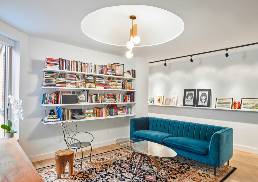 Inredning av ett minimalistiskt mellanstort separat vardagsrum, med ett bibliotek, vita väggar, ljust trägolv och brunt golv