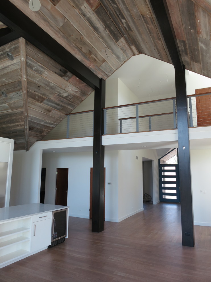 Modern inredning av ett stort allrum på loftet, med vita väggar, mellanmörkt trägolv, en standard öppen spis, en spiselkrans i sten och en väggmonterad TV