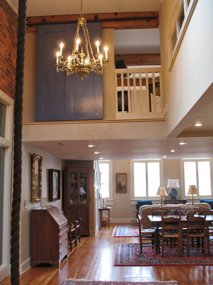 Immagine di un soggiorno tradizionale stile loft con pareti bianche, pavimento in legno massello medio, camino classico e TV nascosta