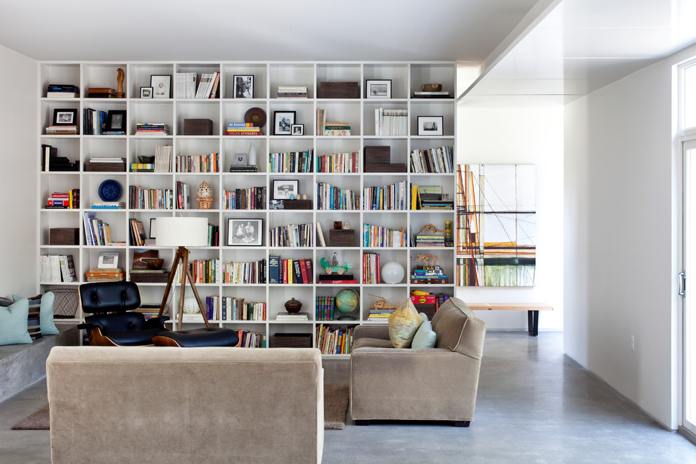 Idee per un soggiorno minimal di medie dimensioni e aperto con pareti bianche, pavimento in cemento e libreria