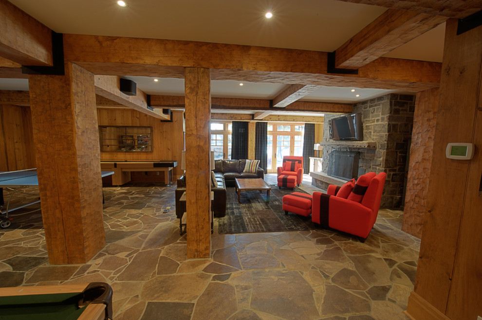 Esempio di un grande soggiorno stile rurale aperto con sala giochi, pavimento in ardesia, camino classico, cornice del camino in pietra e TV a parete