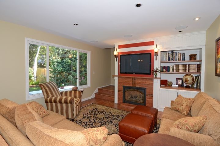 Foto de sala de estar abierta y blanca de estilo americano pequeña con paredes beige, suelo de madera en tonos medios, todas las chimeneas, televisor colgado en la pared y panelado
