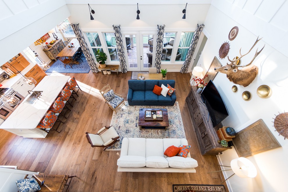 Immagine di un grande soggiorno country aperto con pareti bianche, pavimento in legno massello medio, TV autoportante e pavimento marrone