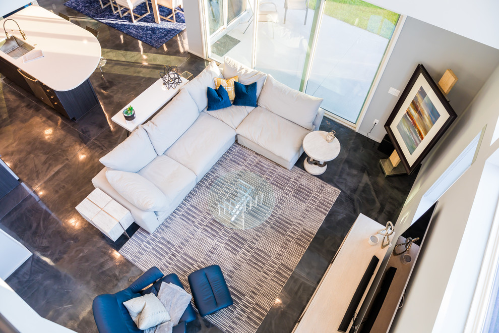 Diseño de sala de estar abierta moderna de tamaño medio sin chimenea con paredes grises, suelo de cemento, televisor colgado en la pared y suelo gris